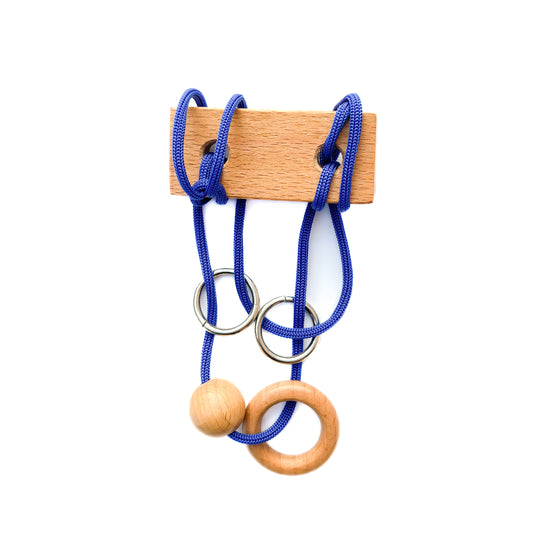 Wooden string puzzle with blue thread on a white background. This classic brain teaser toy challenges players to manipulate the loop of blue thread to disentangle the wooden pieces. 
