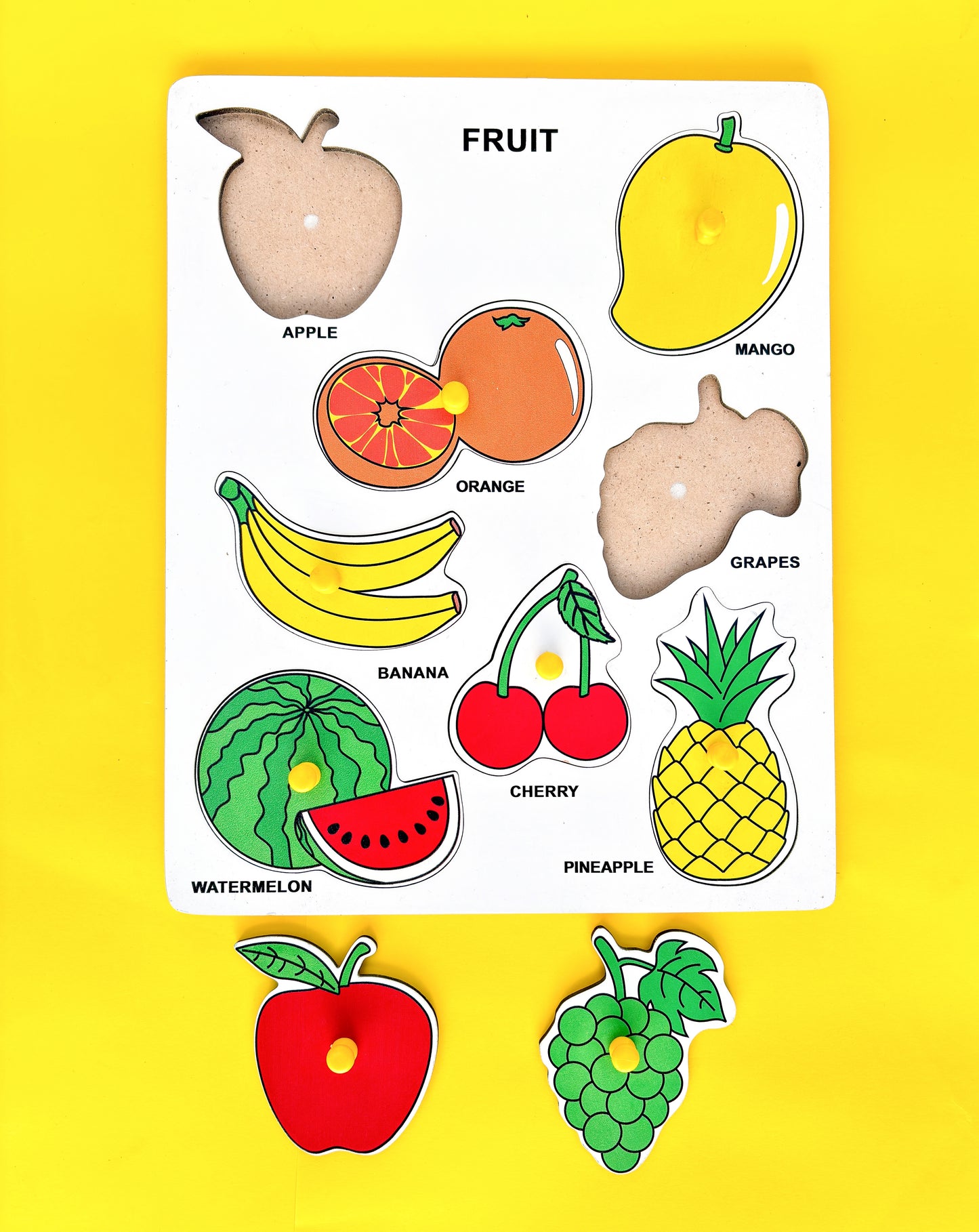  Wooden puzzle with colorful fruit shapes on a yellow background. The text “FRUIT” is displayed at the top of the puzzle, followed by the names of six fruits pictured below: APPLE, MANGO, ORANGE, GRAPES, BANANA, and CHERRY.  WATERMELON and PINEAPPLE are displayed on the right and left side of the puzzle, respectively. This educational toy helps young children learn about different fruits and identify their shapes. 