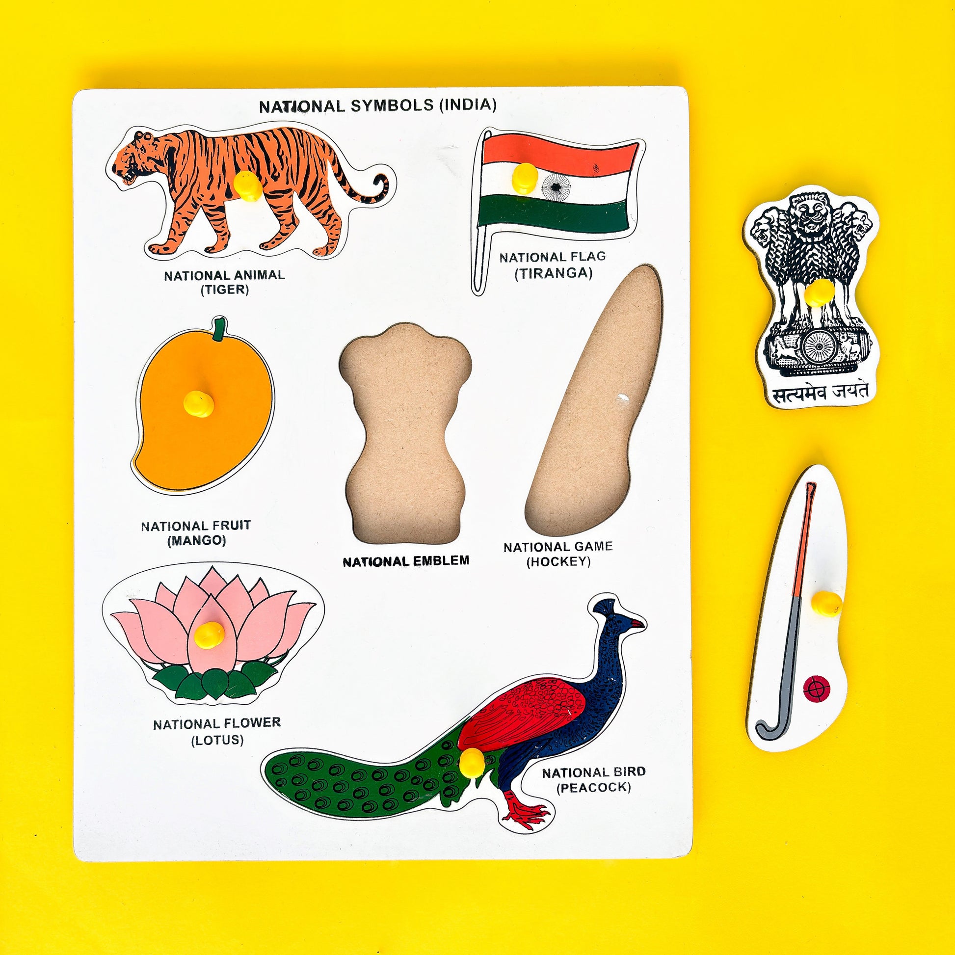 A colorful wooden puzzle map of India shaped like the country, depicting its national symbols. The puzzle includes the Indian national flag (Tiranga), a Bengal tiger (national animal), a mango (national fruit), a hockey stick and ball (national game), a lotus flower (national flower), a peacock (national bird), and the national emblem of India (Satyameva Jayate).