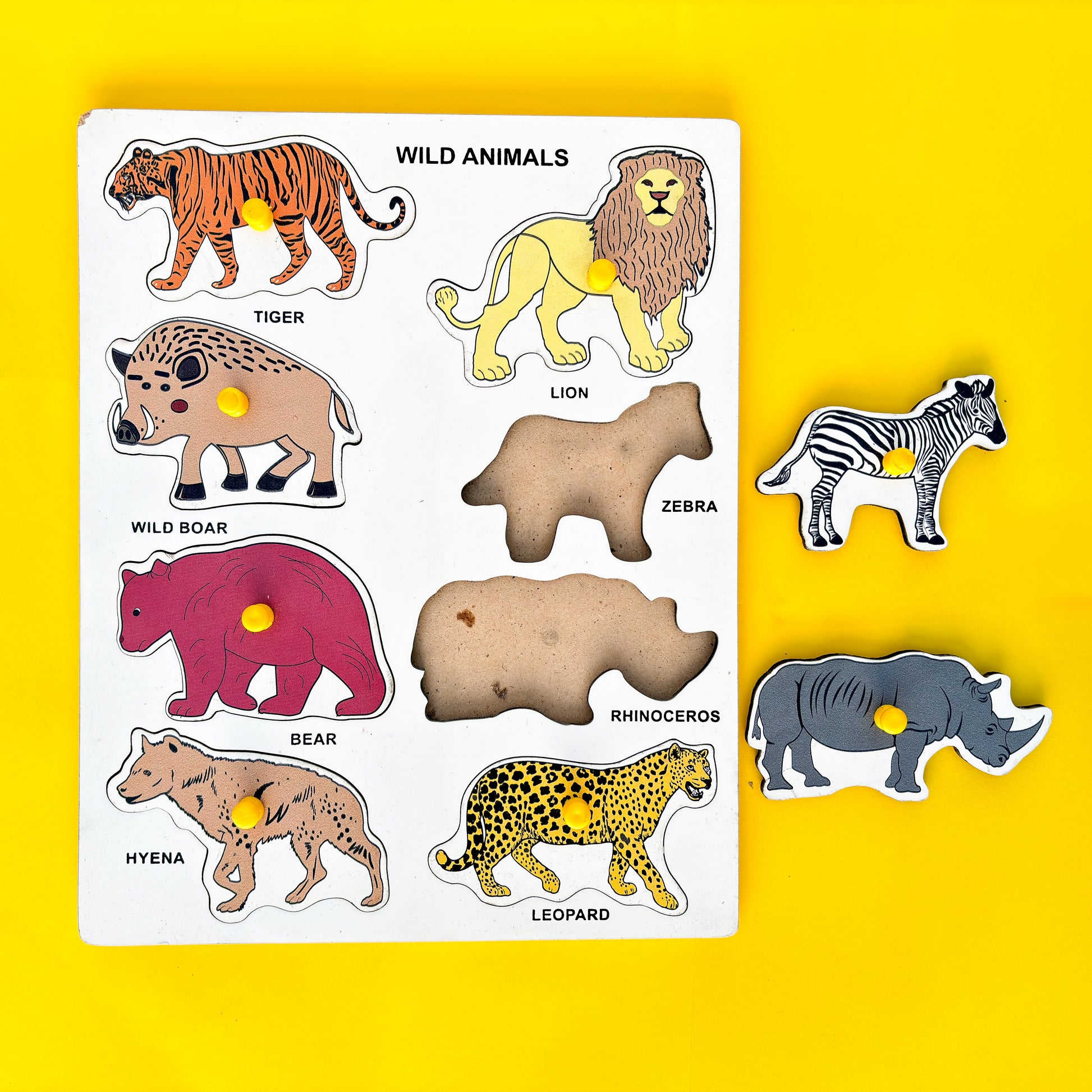 Wooden puzzle with wild animals on a yellow background. The animals include a tiger, lion, wild boar, zebra, bear, rhinoceros, hyena, and leopard.